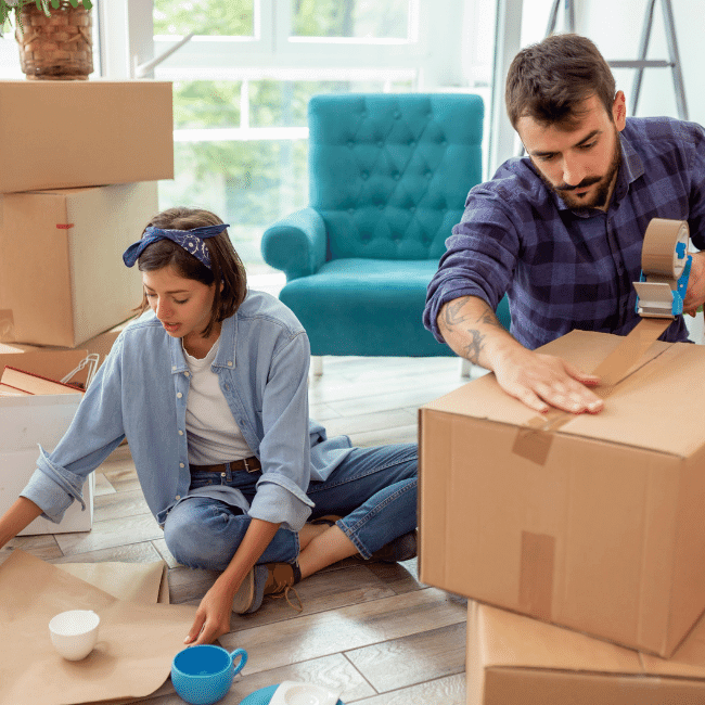 Selling-Your-House-How-to-Emotionally-Prepare image of a couple sitting in the lounge room packing boxes