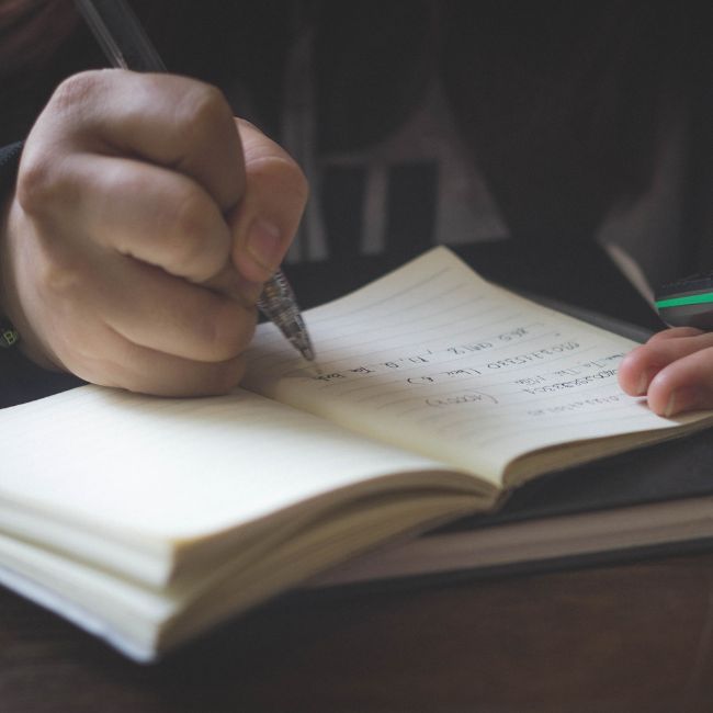 Person writing in a notebook as they prepare for their estate planning session