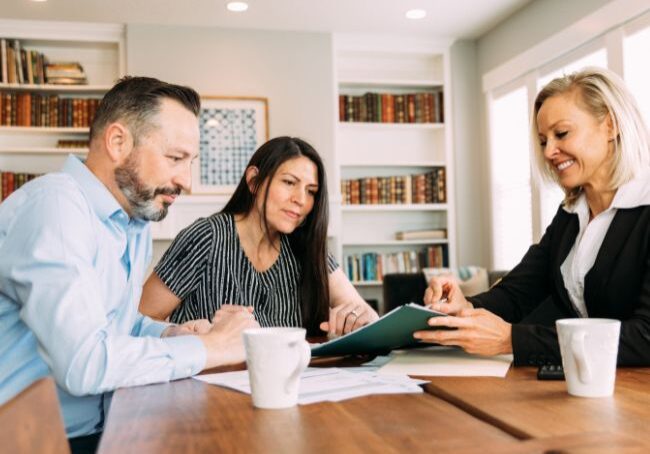 A couple at a table talking with a lady who is advising them on investment property