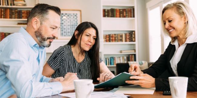 A couple at a table talking with a lady who is advising them on investment property